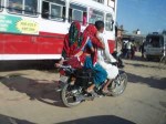 インド、原色のサリーをまといバイクに乗るラジャスタン女性