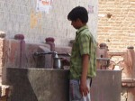 インド、共同水道で水を汲む少年